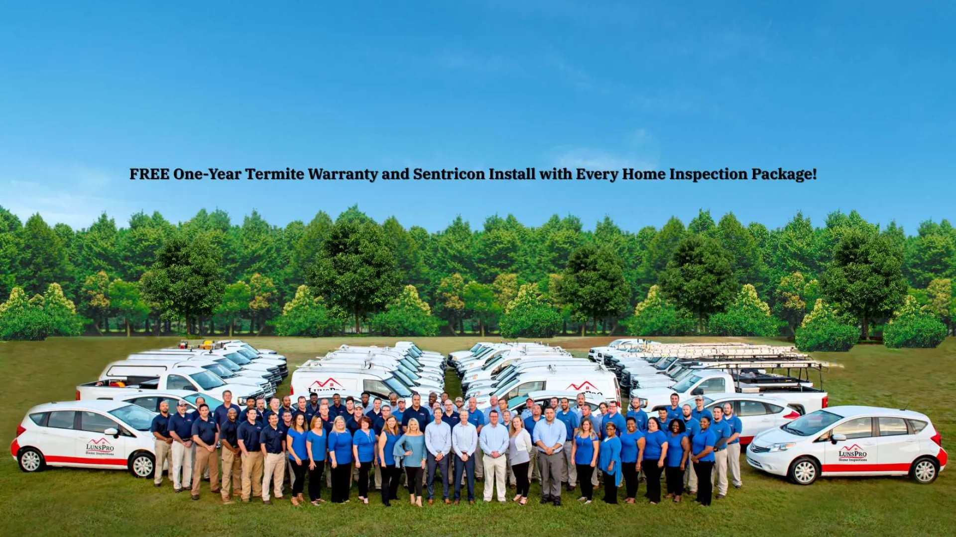 Large team and fleet of branded vehicles assembled on grass with trees and clear blue sky background