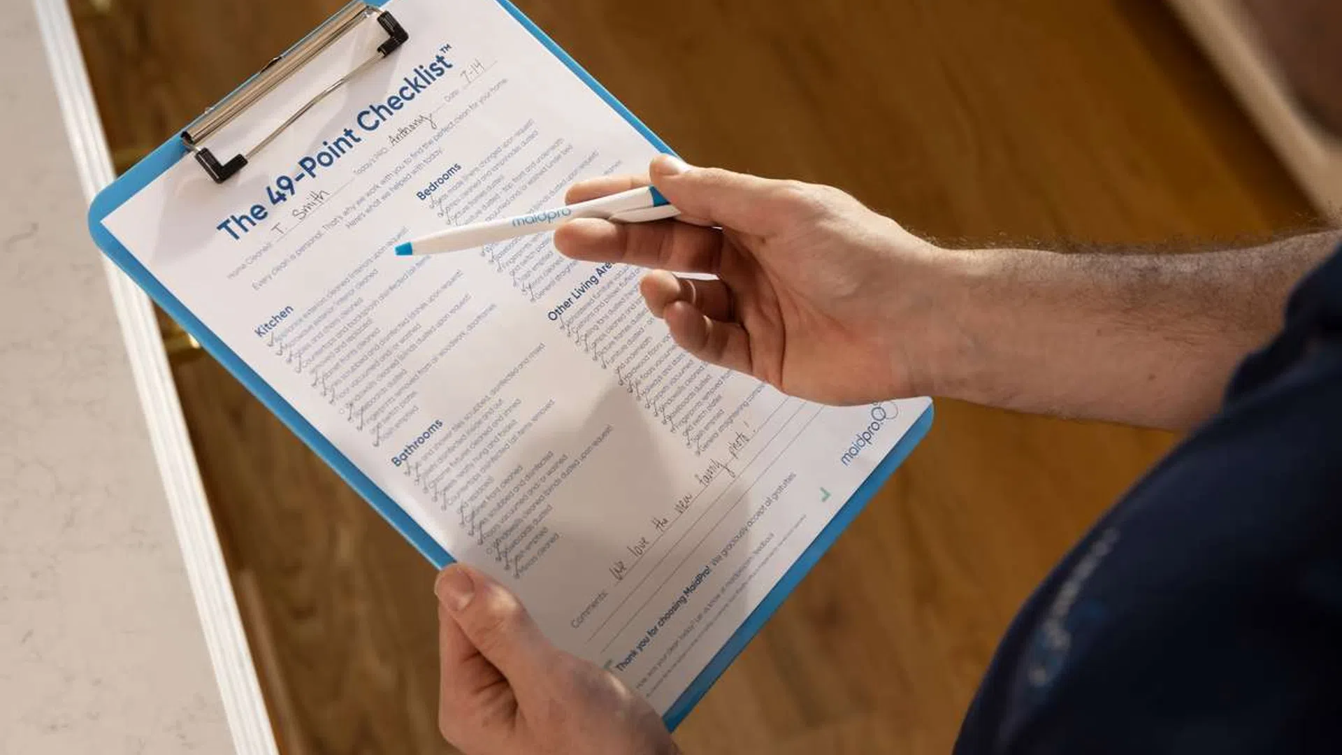 Person holding a clipboard with a detailed 49-point checklist and marking items with a pen
