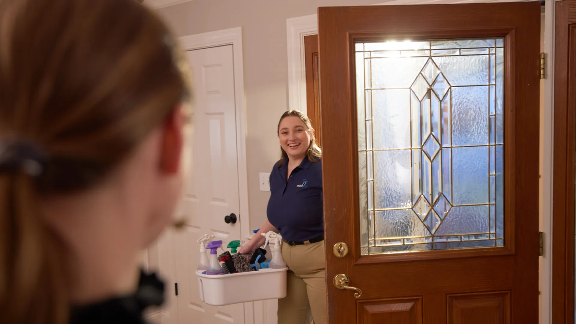 a woman holding a cleaning caddy