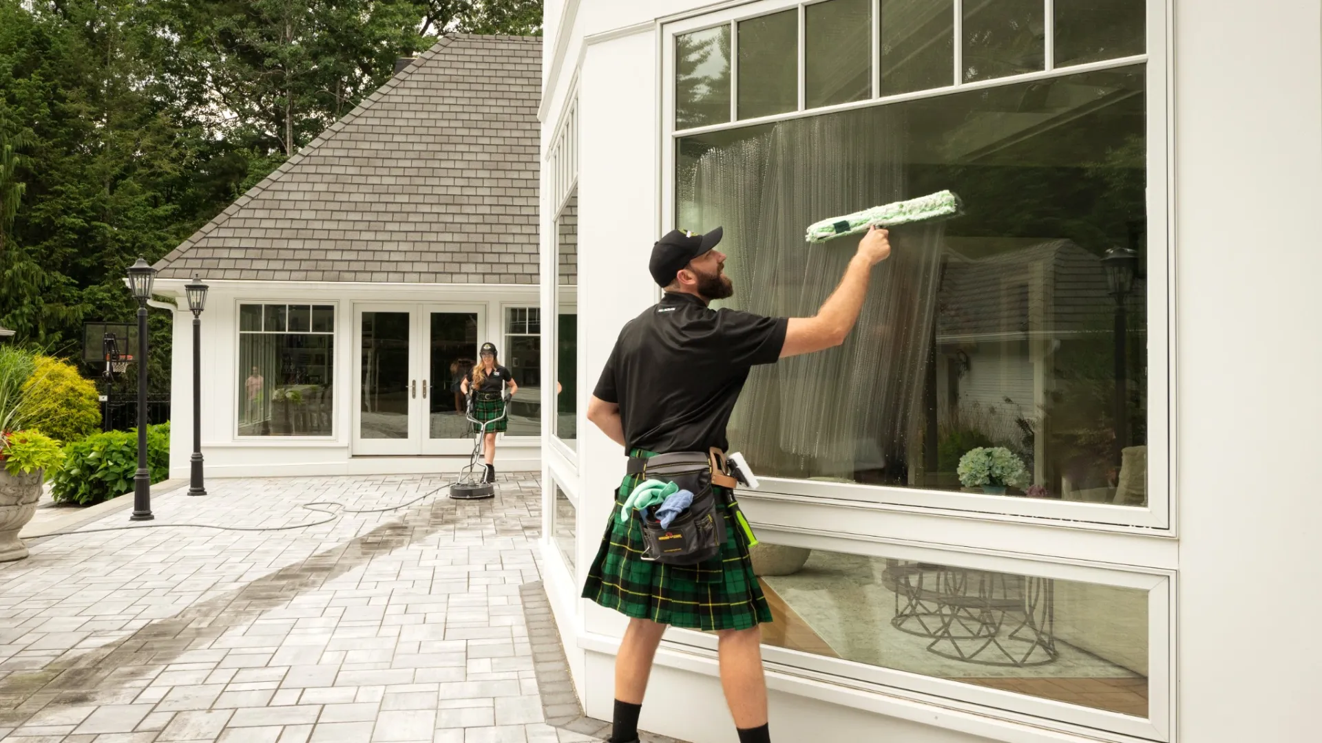 A man and woman cleaning the exterior of a house