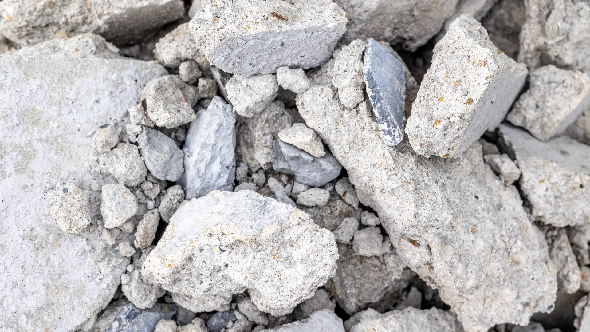 Pile of broken gray concrete rubble with mixed small and large fragments on the ground.