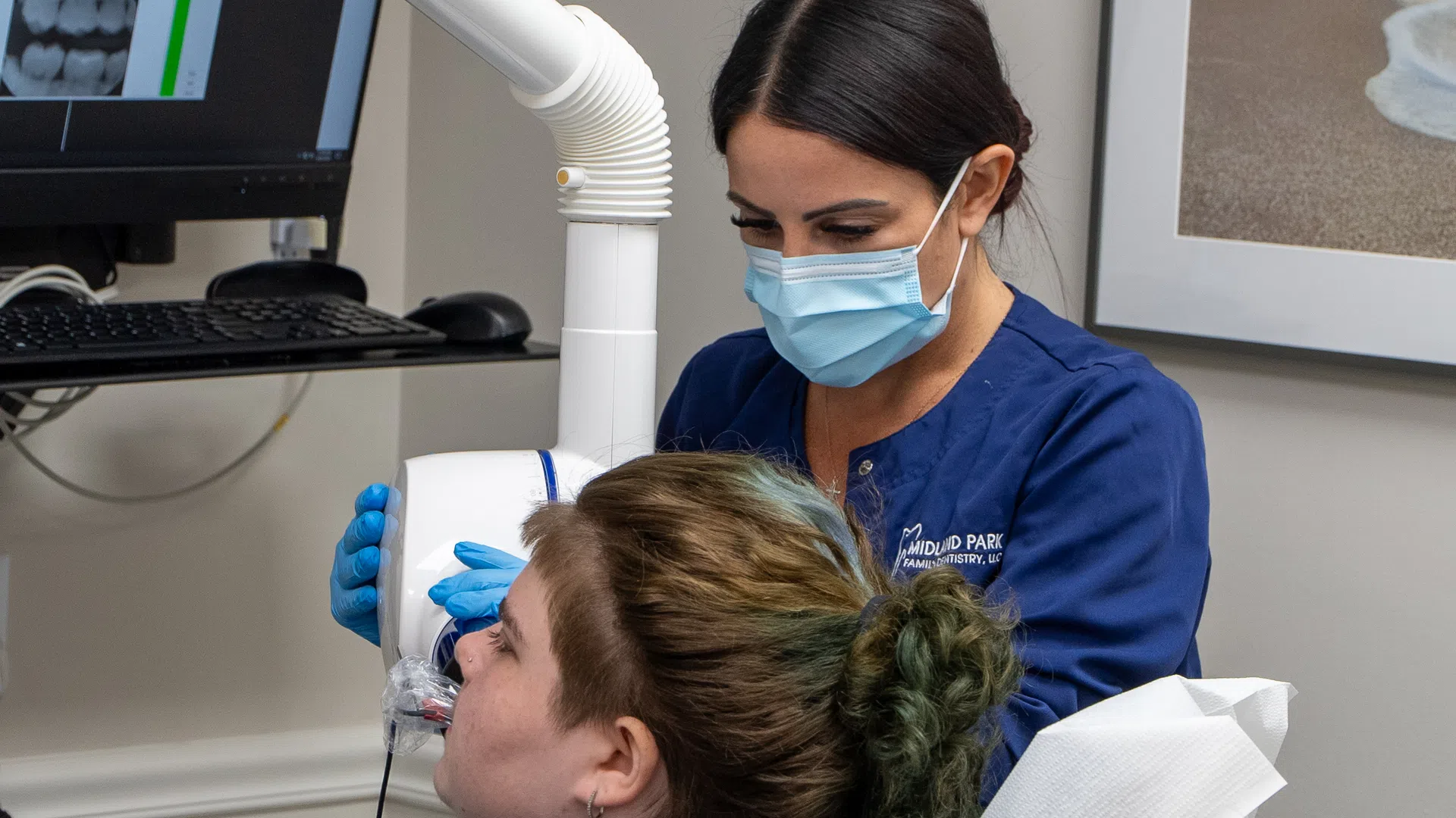 Dentist wearing mask and gloves using dental equipment to examine patient's teeth during a dental visit.