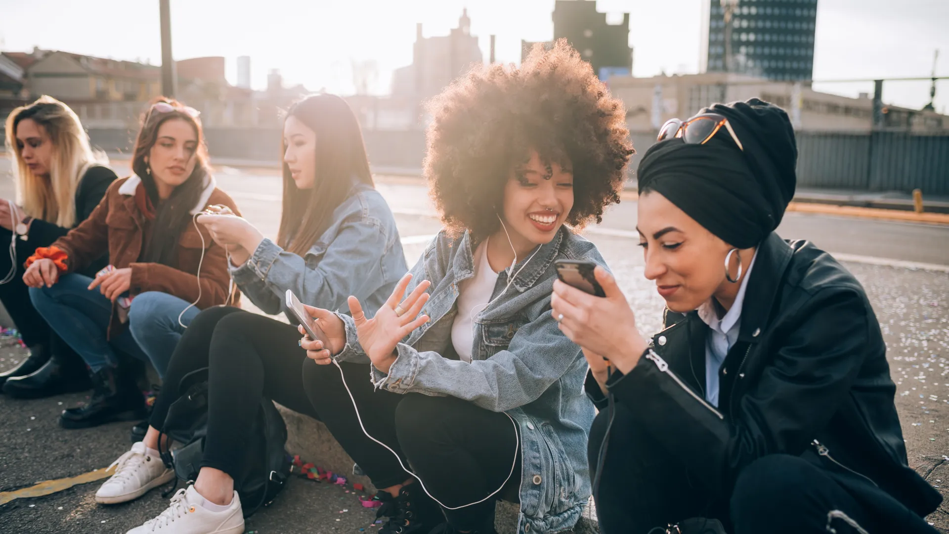 a group of people sitting on the ground looking at their phones