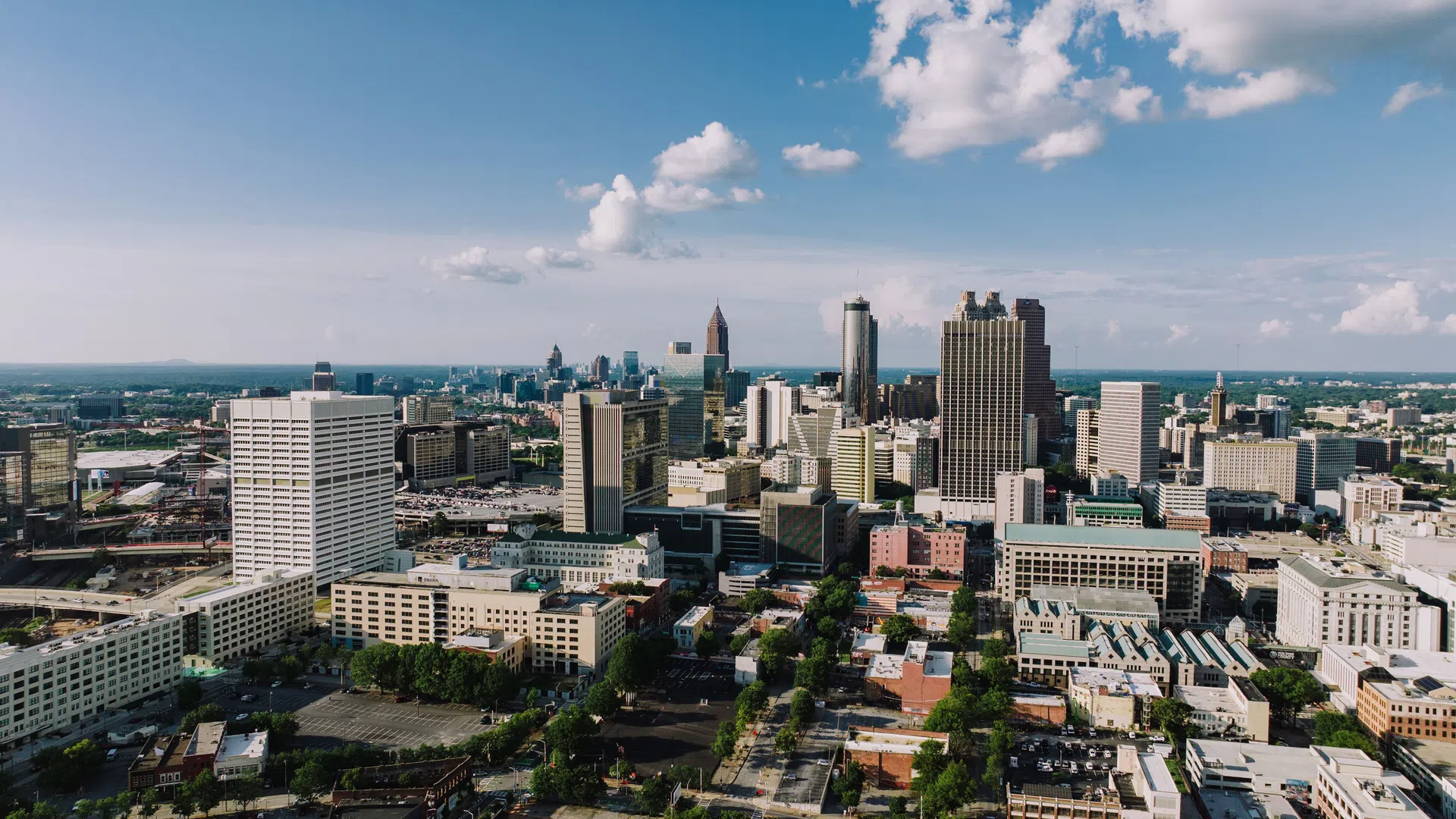 Aerial view of a city skyline with tall buildings under a partly cloudy blue sky during daytime.