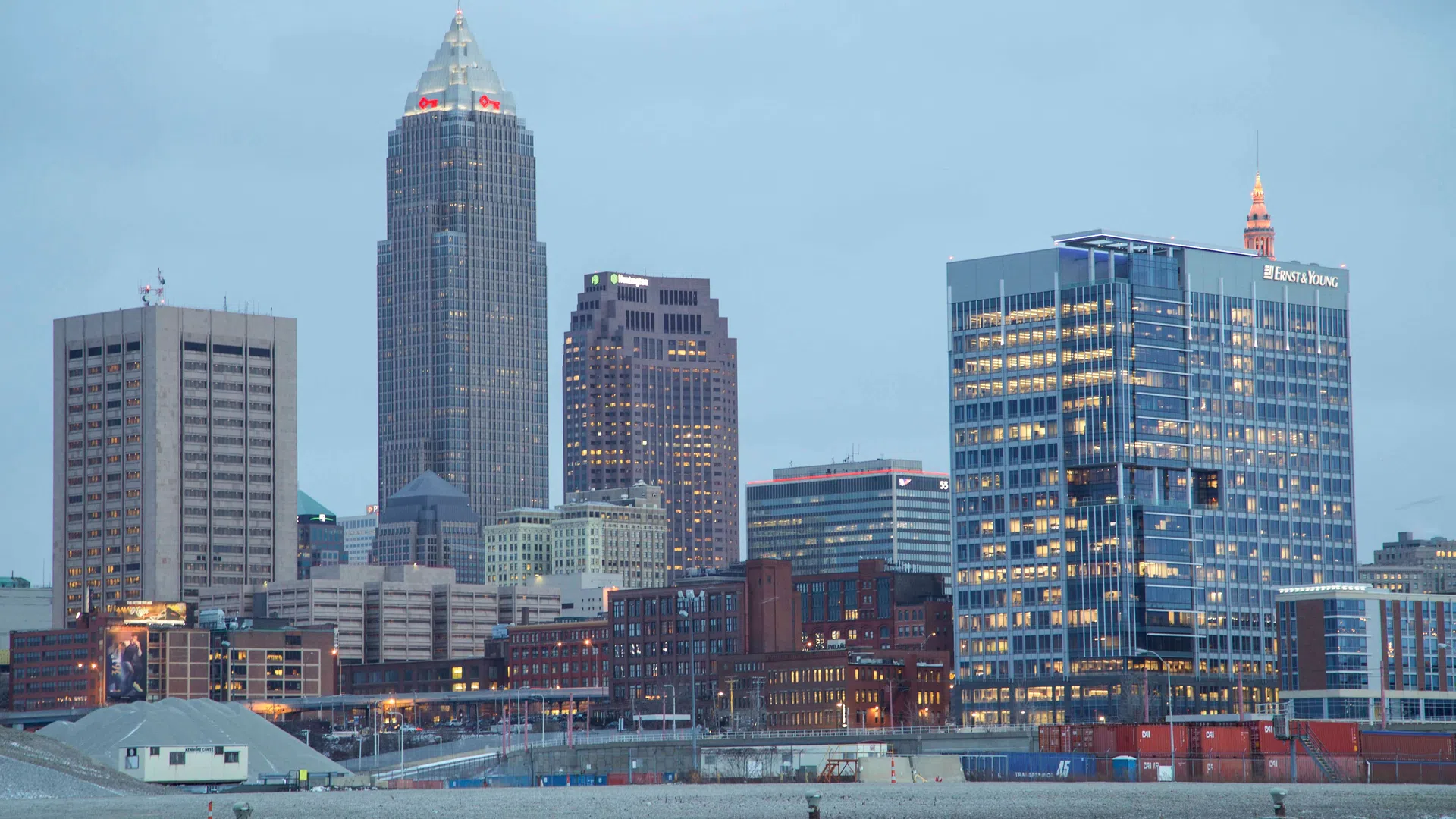 Cleveland city skyline at dusk with illuminated skyscrapers and waterfront in the foreground.