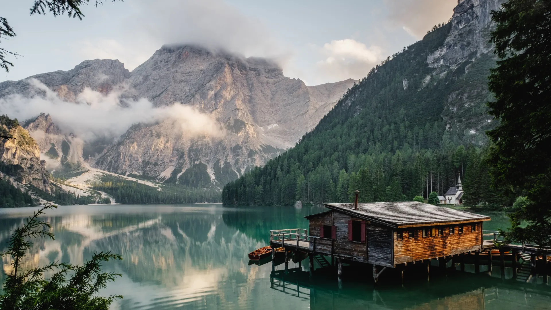 a house on a dock by a lake with mountains in the background