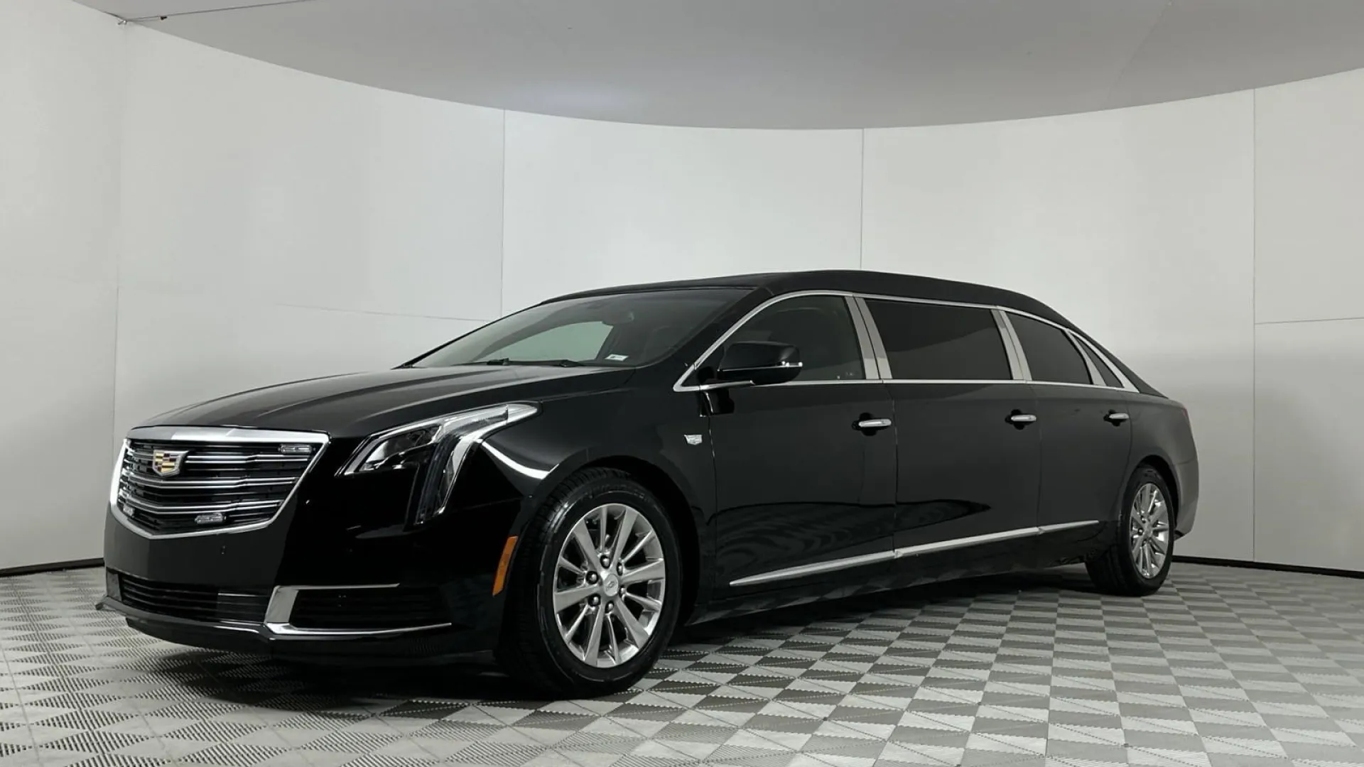 Sleek black Cadillac limousine parked on a patterned floor in a studio setting.