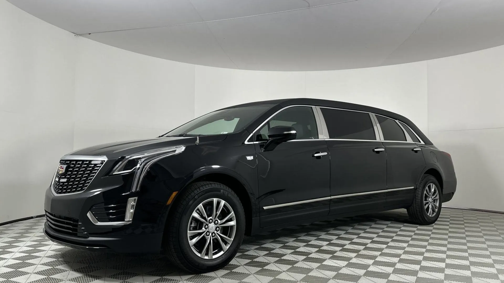 Sleek black Cadillac limousine parked on a patterned floor in a studio setting.