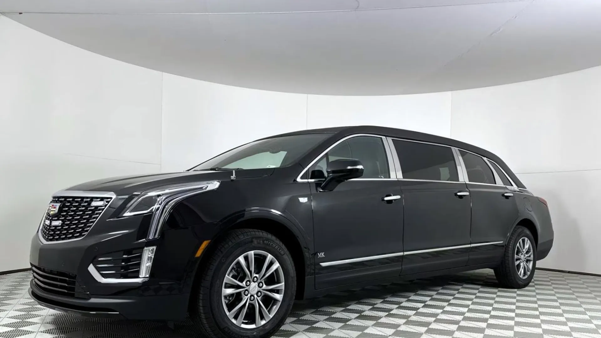 Black Cadillac XT5 SUV displayed in a showroom with a modern background.