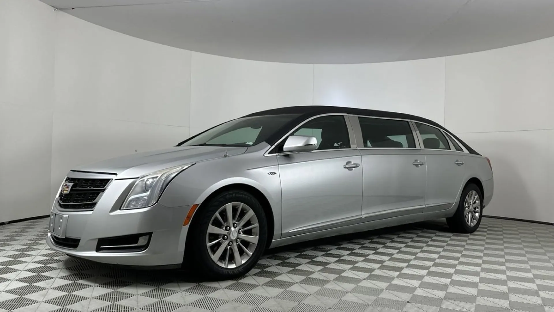 A sleek silver luxury limousine parked in a well-lit showroom environment.