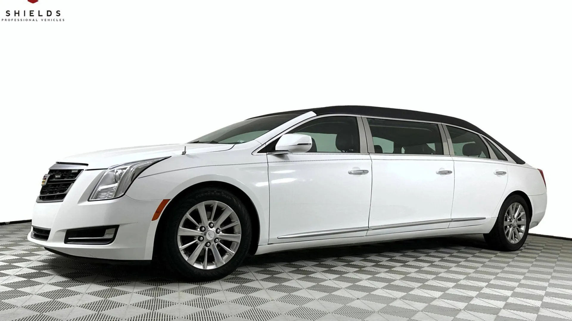 A sleek white luxury sedan showcased in a professional setting with a checkered floor.