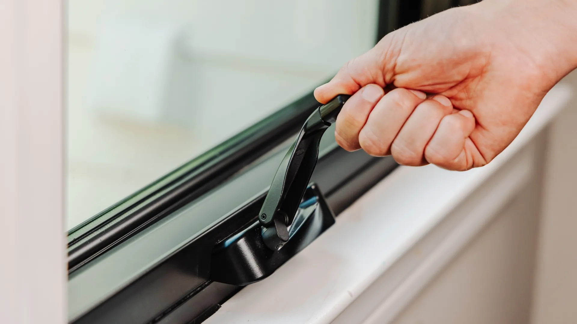 Infinity Windows - Turning the crank on a black fiberglass casement window