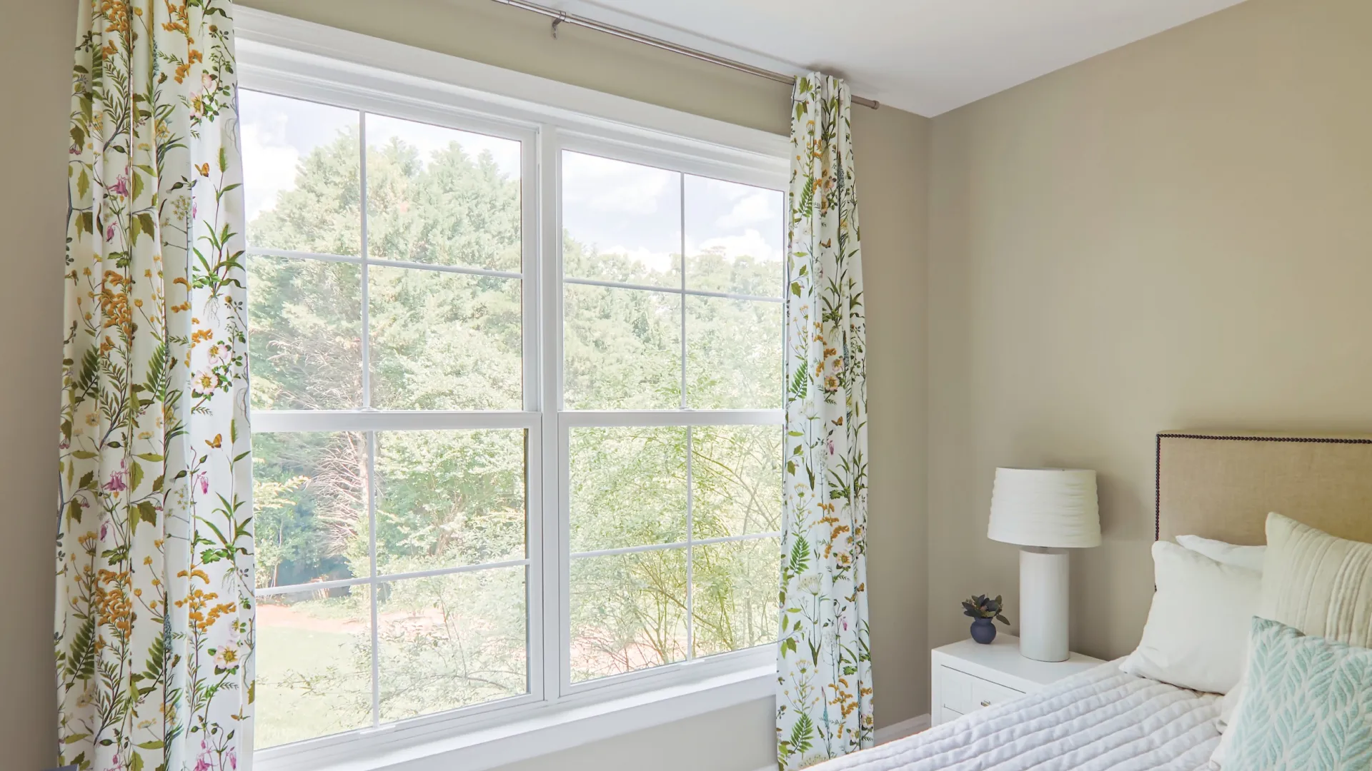Bedroom with 2 double hung white windows overlooking the back yard.