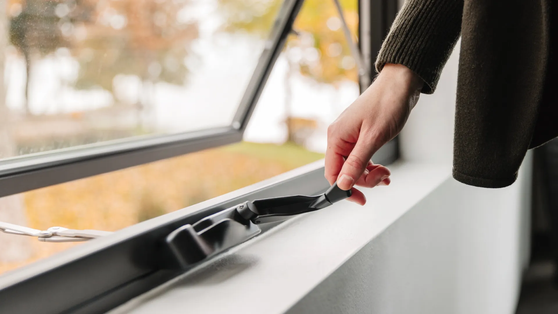 A person operating an awning window to open for fresh air