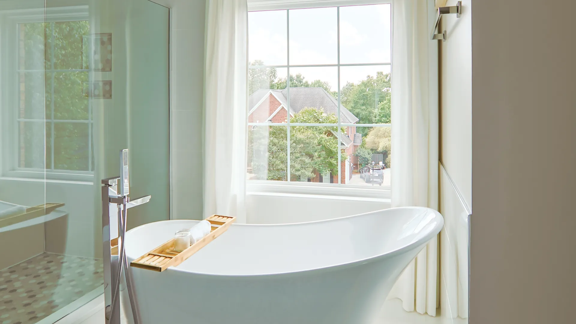Elegant bathroom with a freestanding tub and large window showcasing lush greenery outside.
