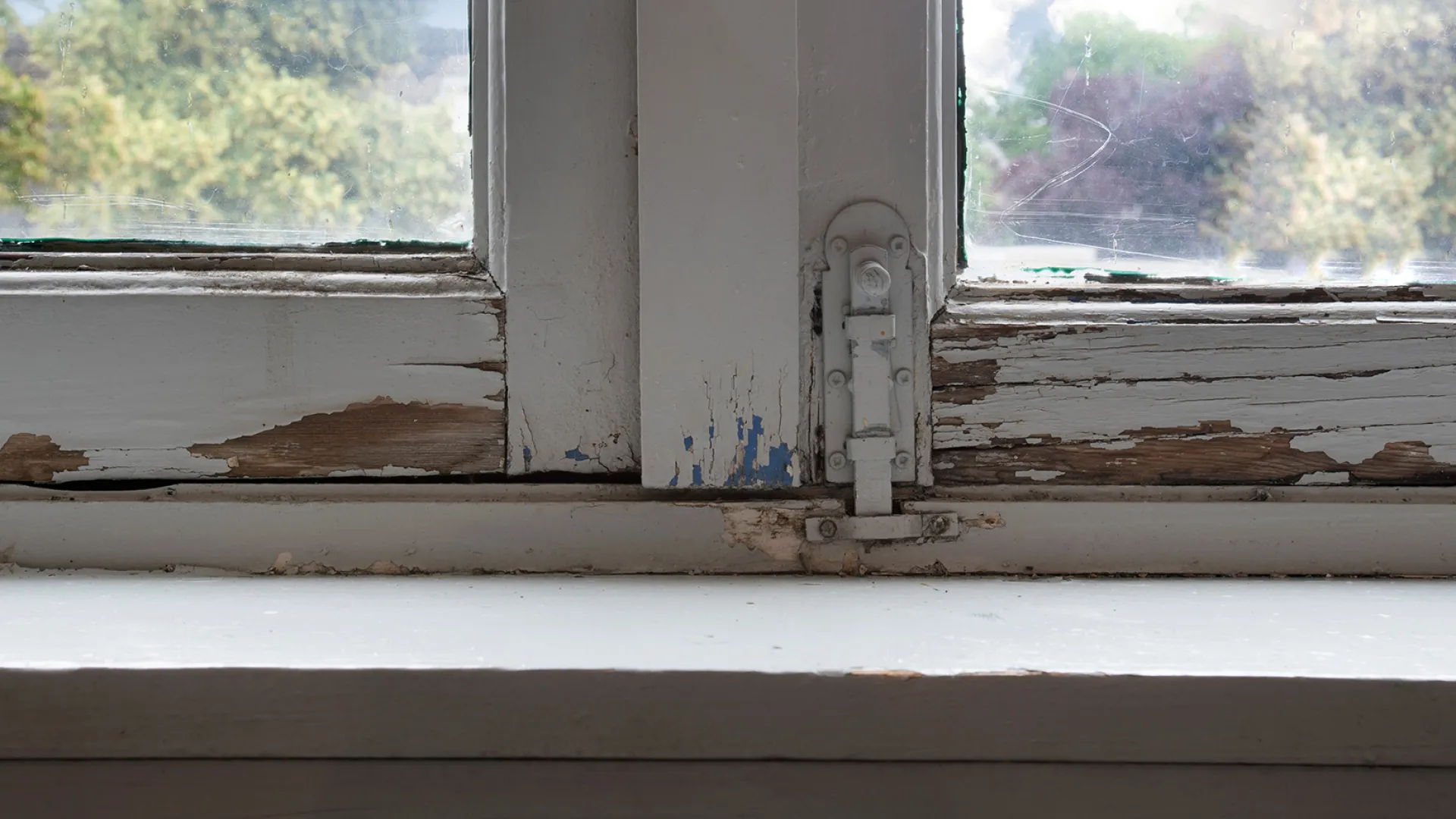 Window frame with chipped paint and wood rot