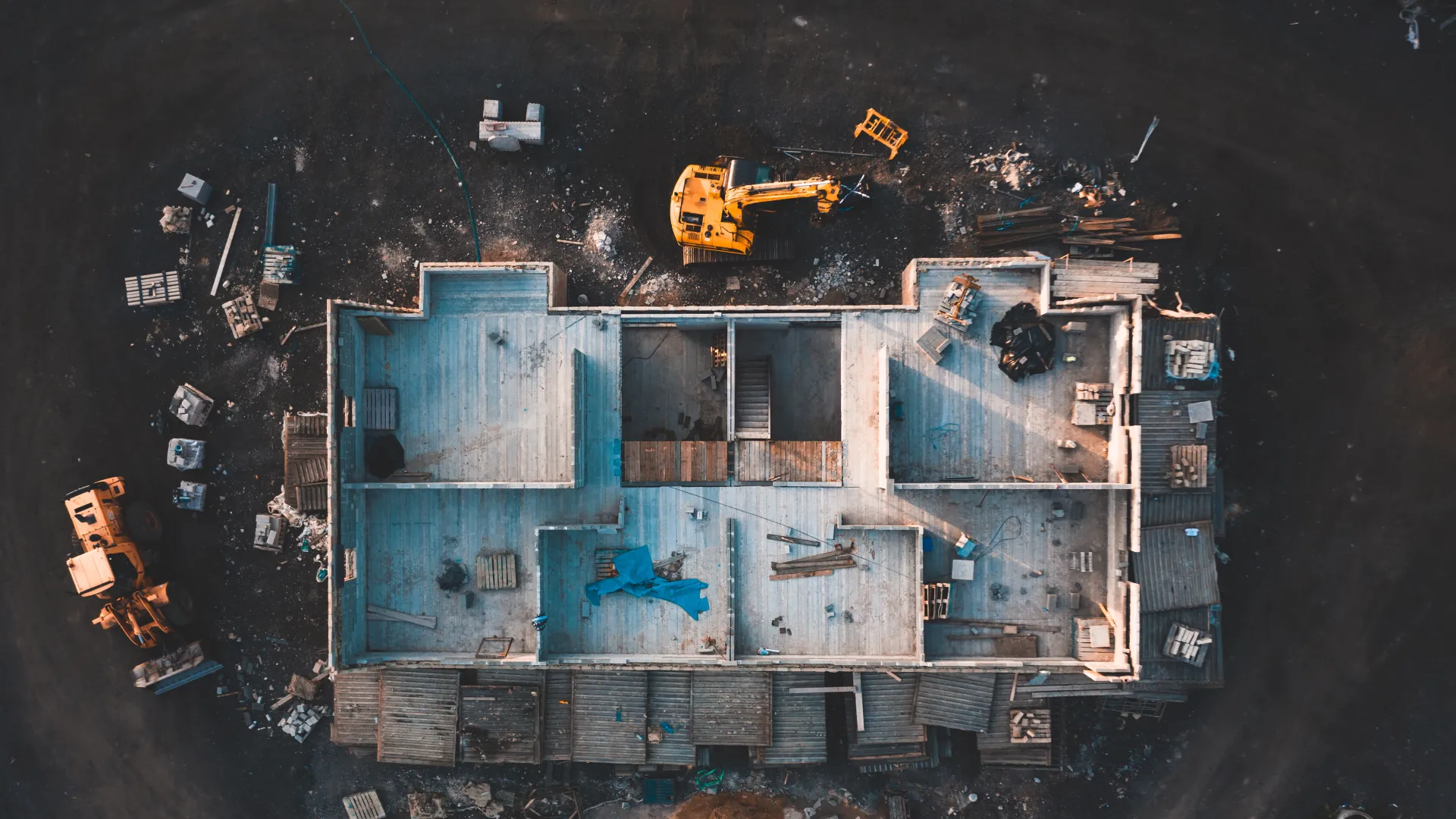 Aerial view of a house under construction with machinery and building materials scattered around the site.