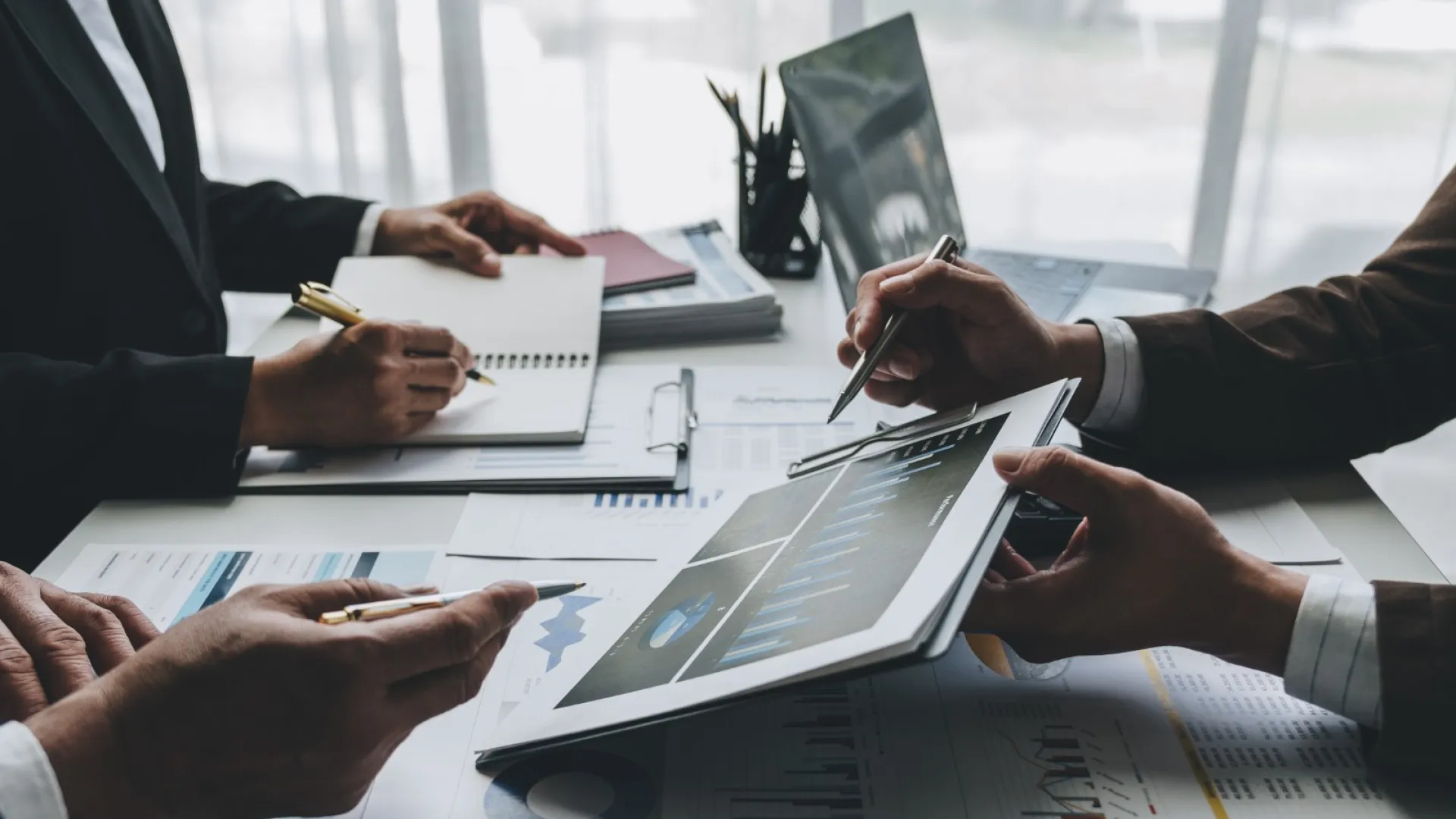 Business professionals analyzing charts and data on a tablet and documents during a meeting