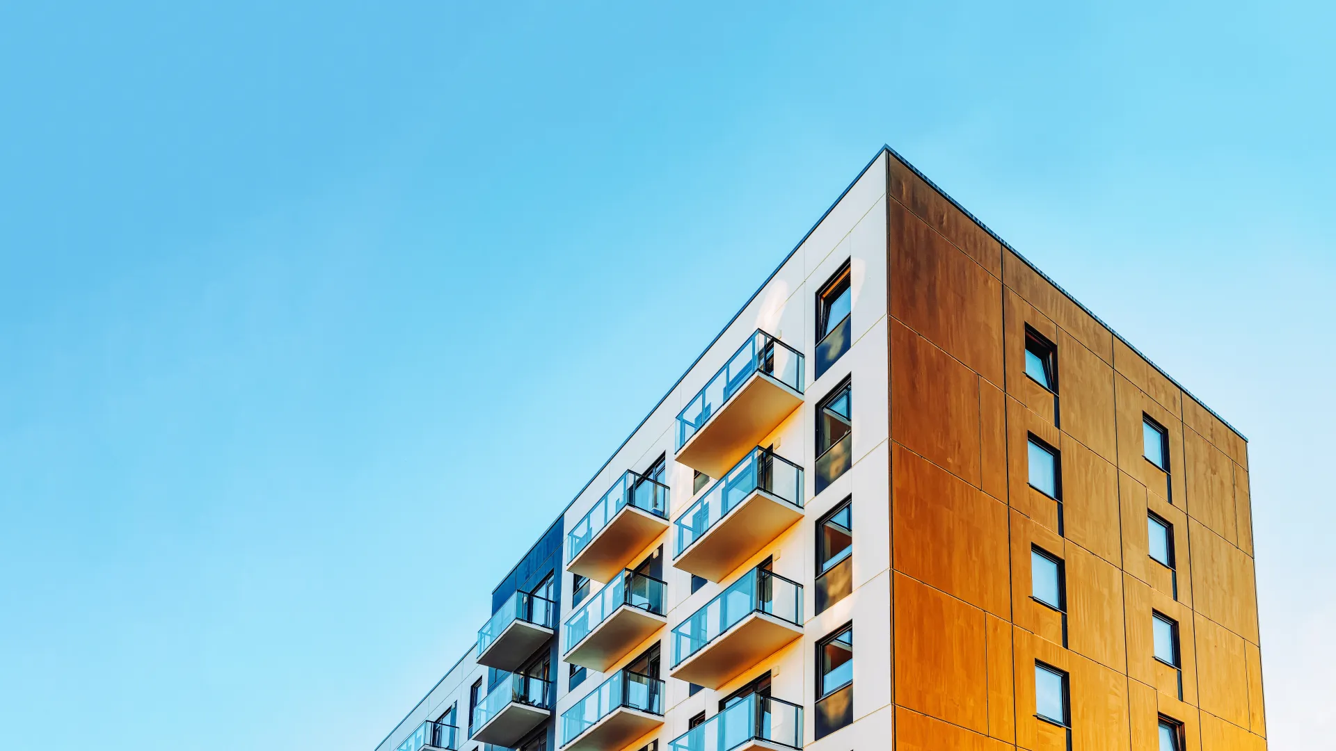 Modern apartment building with balconies under clear blue sky during daytime