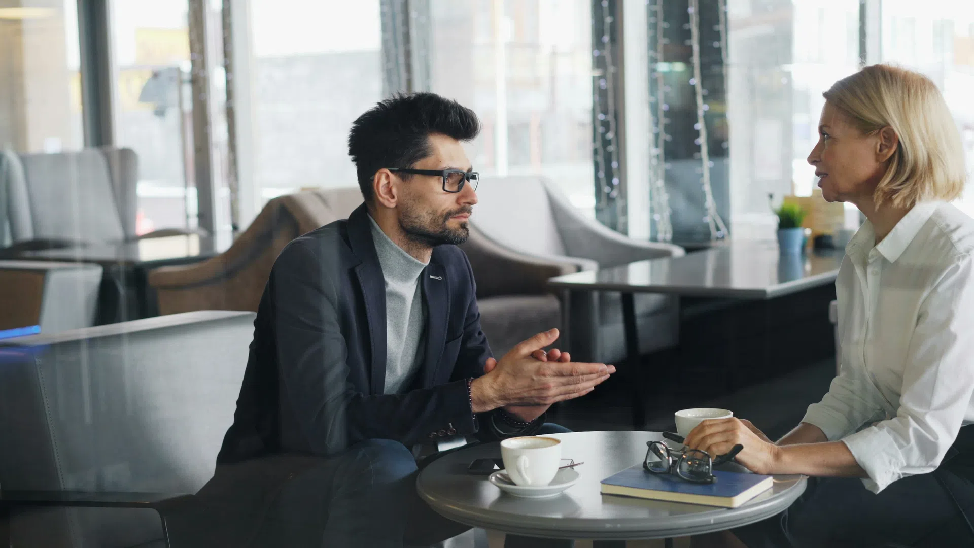 Two business professionals having a focused discussion over coffee in a modern office lounge area.