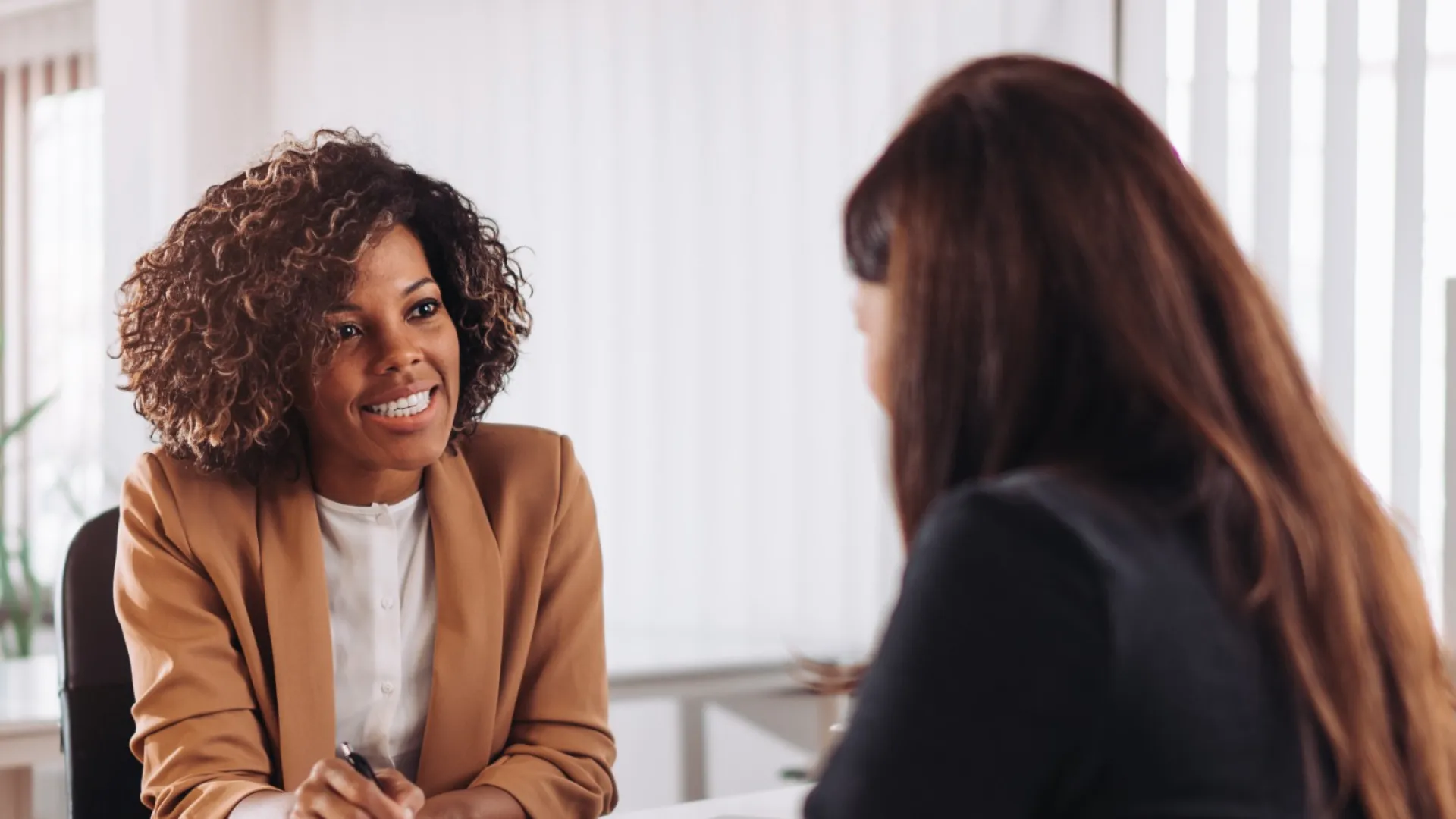 Two professional women having a friendly business meeting in a bright modern office setting.