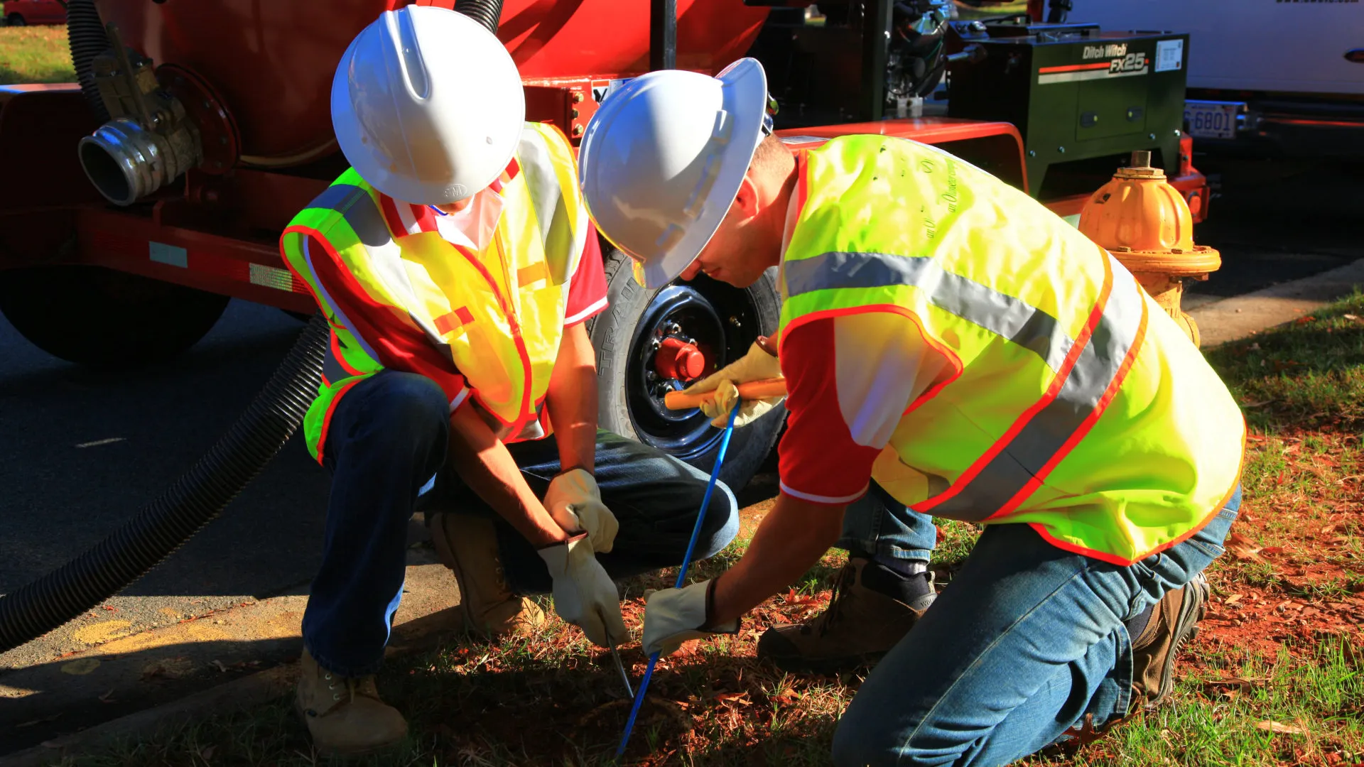 a few men wearing safety vests and working on a car