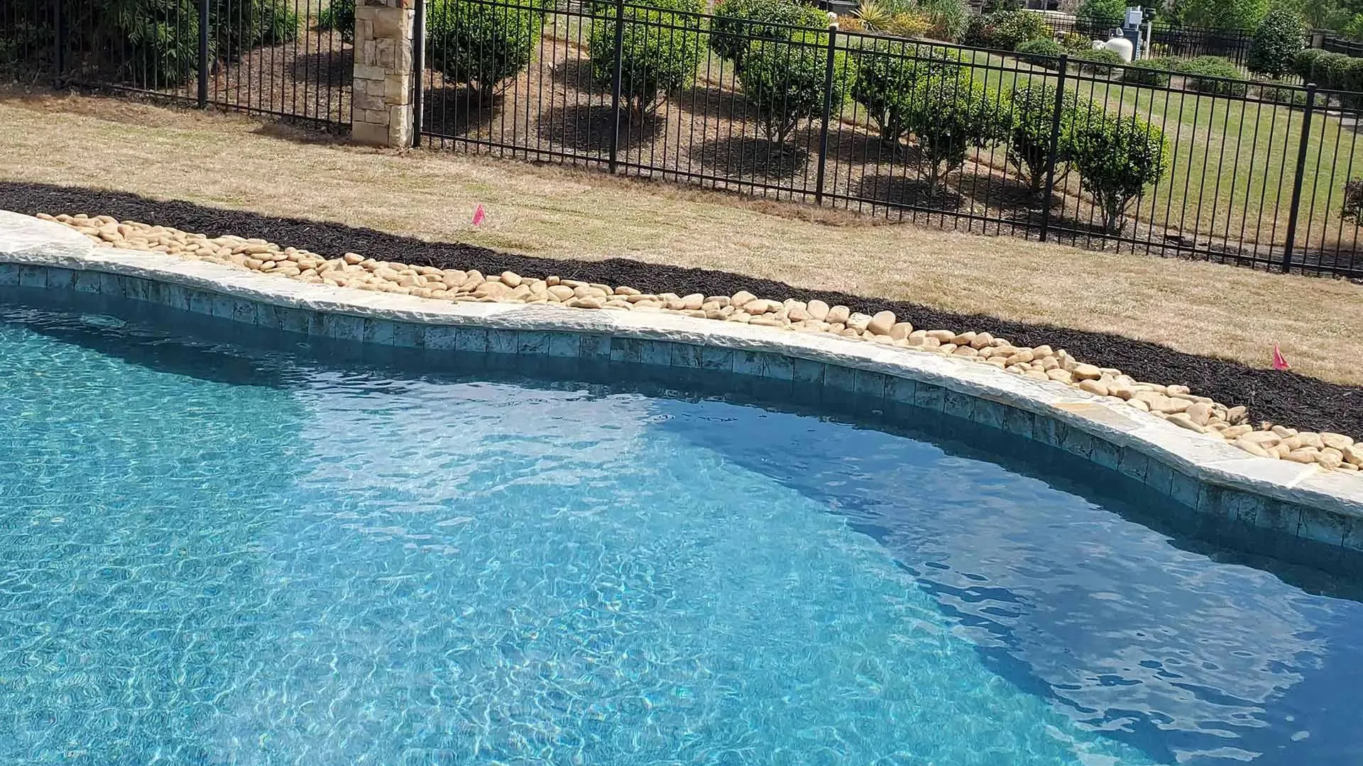 a pool with rocks and a fence around it