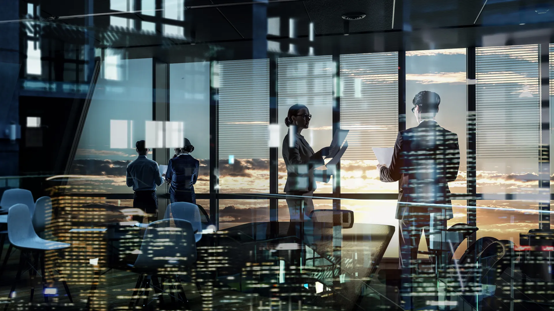 Business professionals working in a modern office with city skyline and sunset reflections on glass walls.