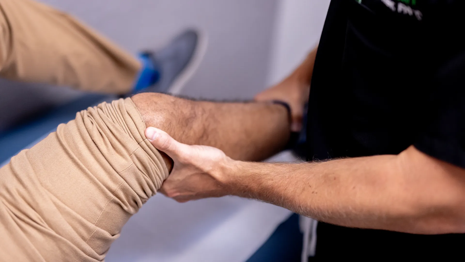 Physical therapist performing knee rehabilitation exercises by supporting patient's bent leg.