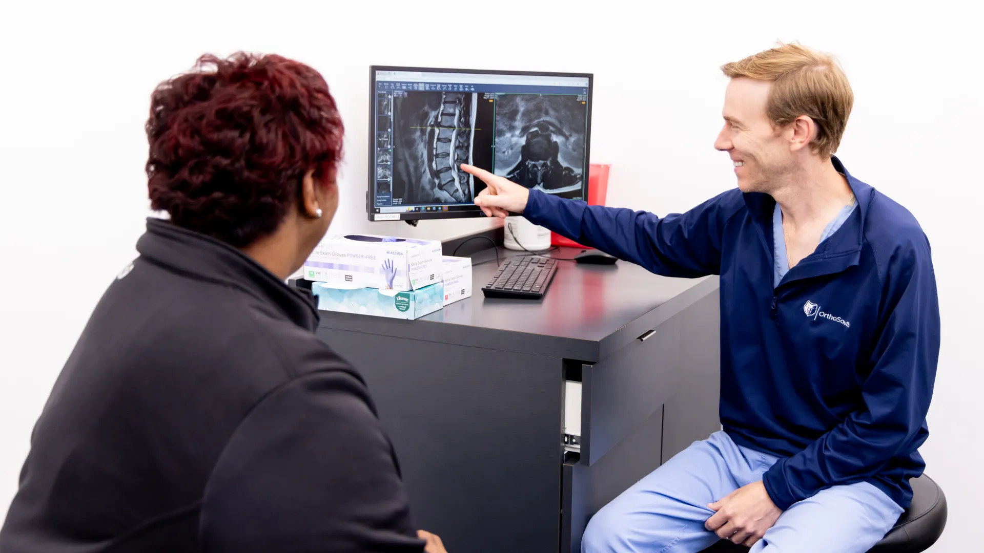 A healthcare professional discussing imaging results with a patient in a modern clinic setting.