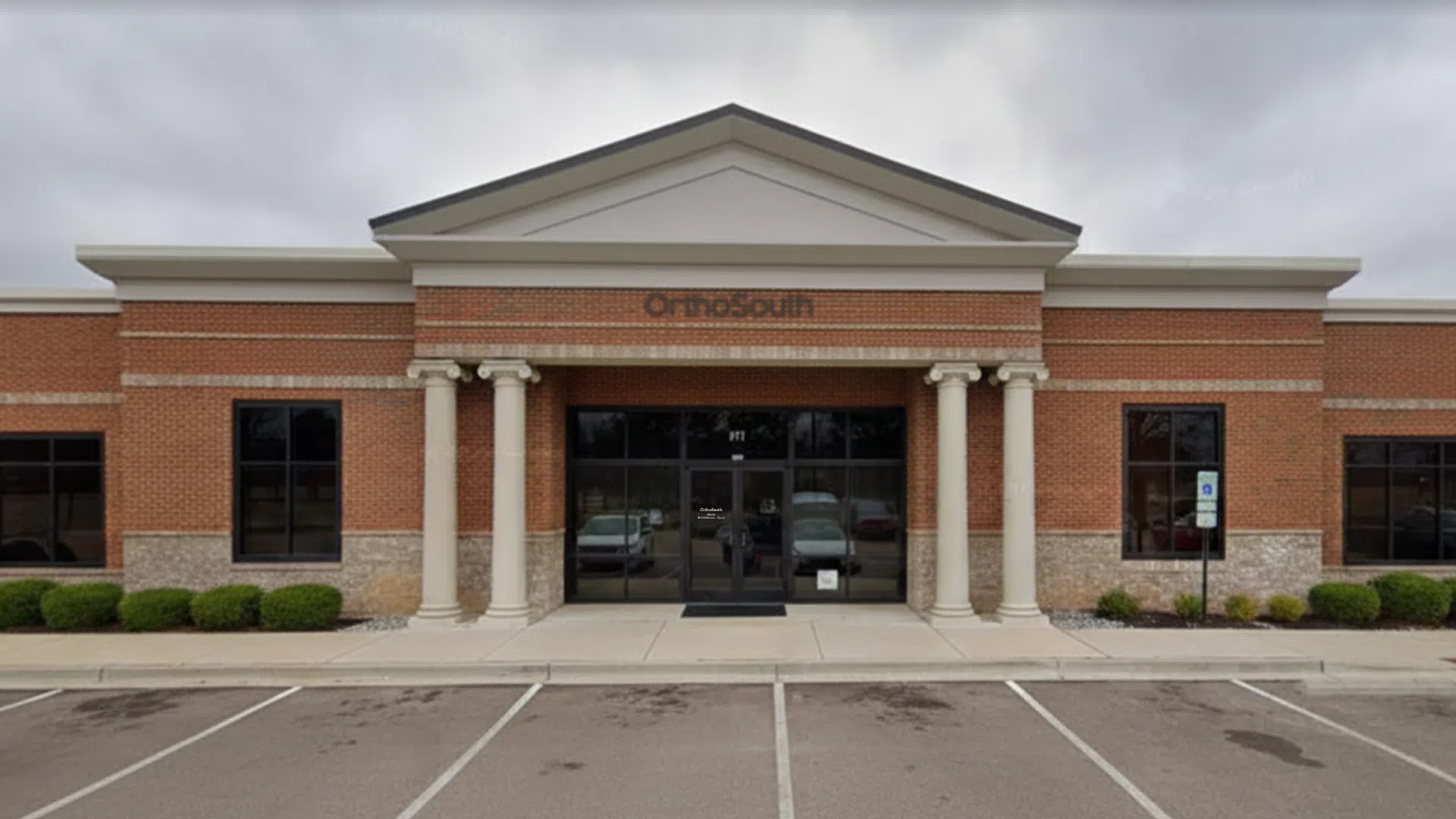 Brick medical office building with columns and OrthoSouth sign above entrance on cloudy day