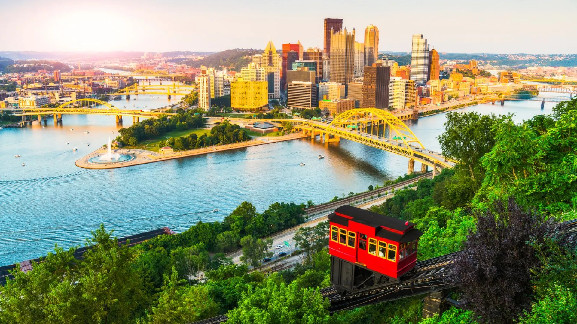 a train on a bridge over a river with a city in the background