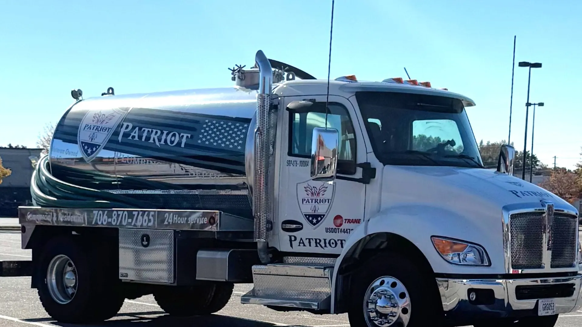 White Patriot branded tanker truck parked in a lot under clear blue sky.