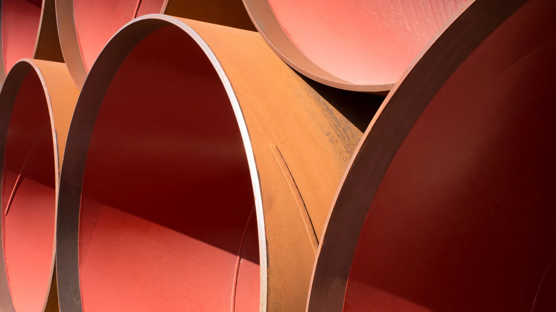 Close-up of large industrial rusty steel pipes stacked together, showing circular openings and textures.