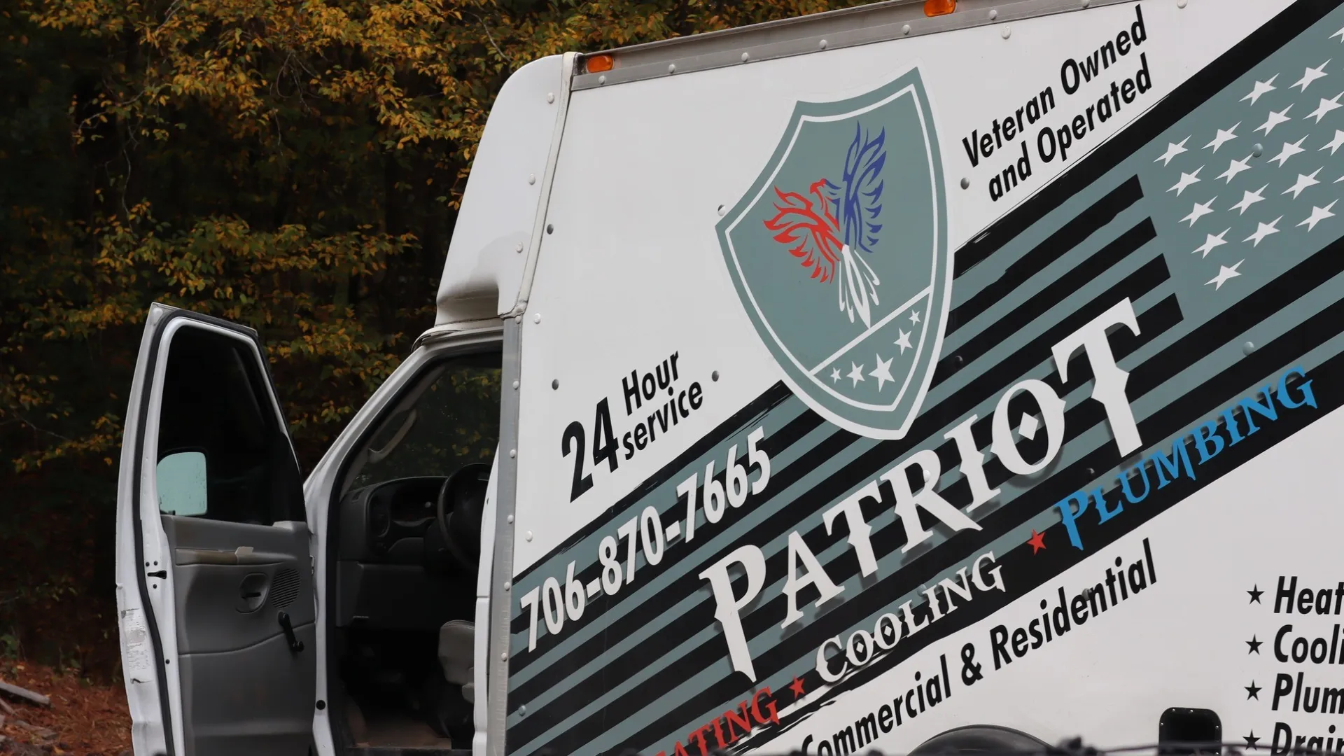 Patriot service van with heating, cooling, and plumbing logo and contact number parked with open door.