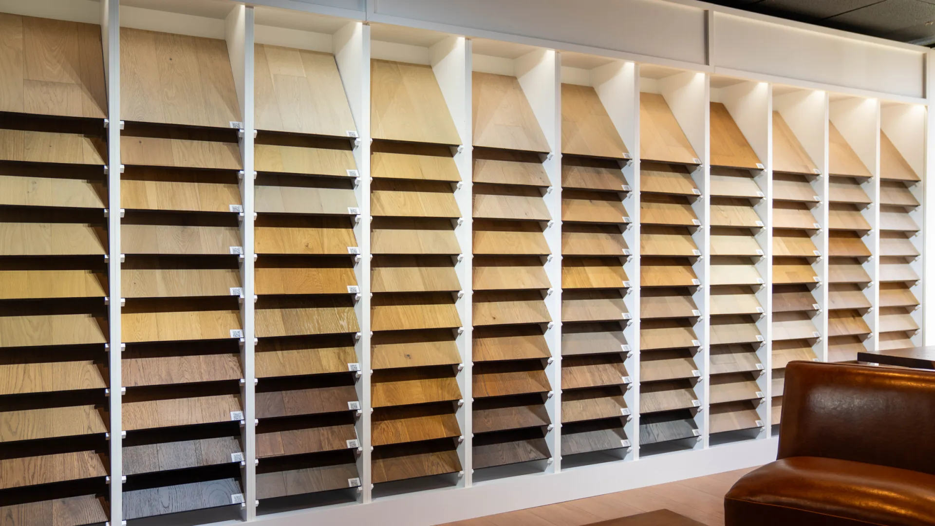 Wall display of various wood veneer samples in multiple shades with a leather chair and wooden table in foreground