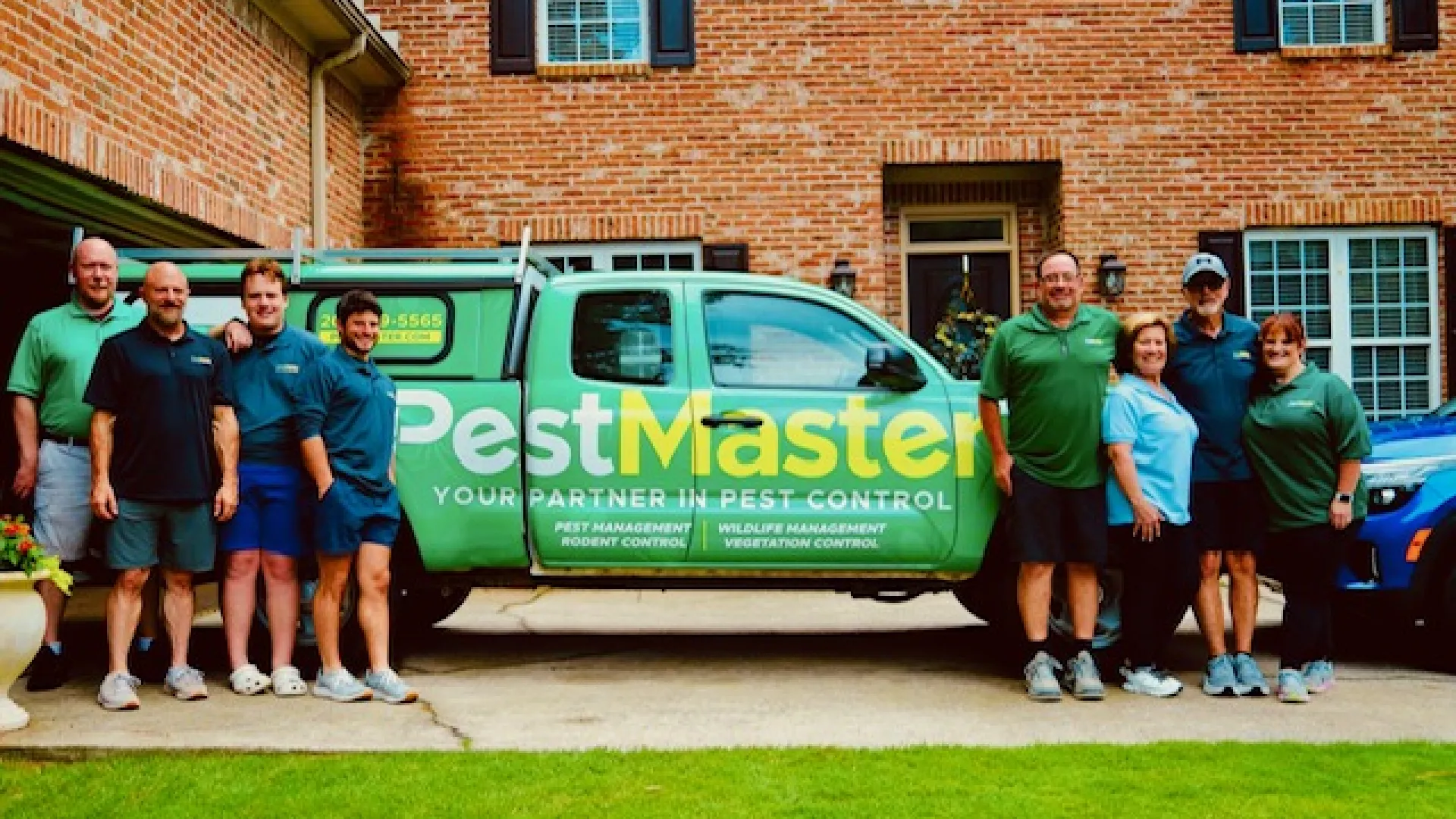 PestMaster pest control team posing beside green company truck, family owned and operated