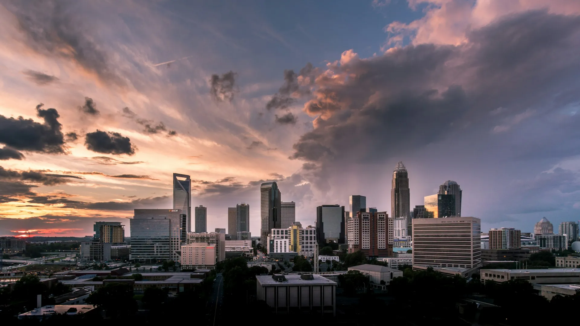 Charlotte city skyline at sunset with dramatic clouds and high-rise buildings in vibrant evening light