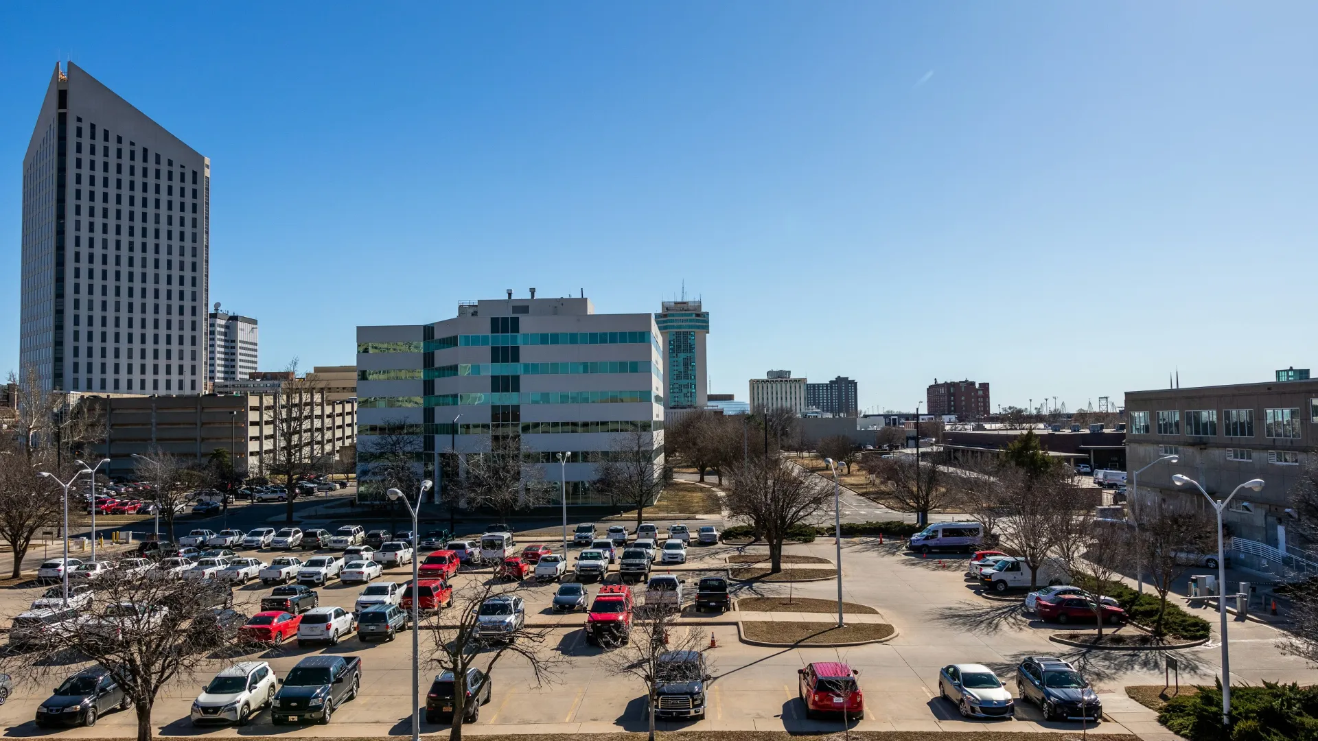 City skyline with modern buildings and a busy parking lot under clear blue sky on a sunny day