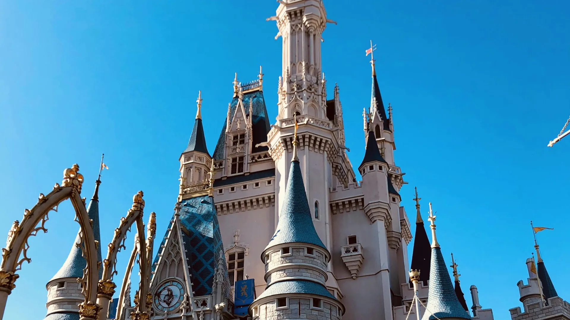 Fairytale castle with blue turret roofs under clear blue sky at a popular theme park