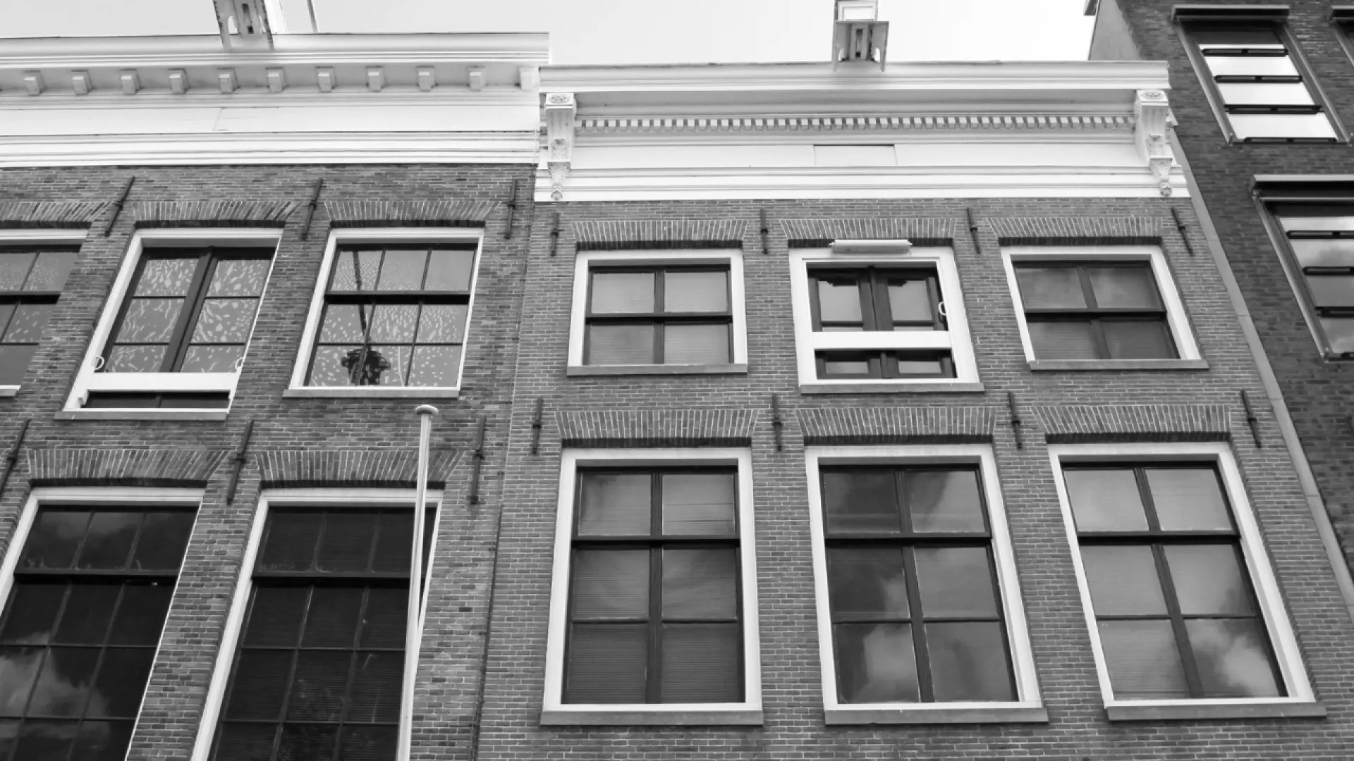 Black and white photo of traditional brick buildings with multiple windows under a decorative roofline.