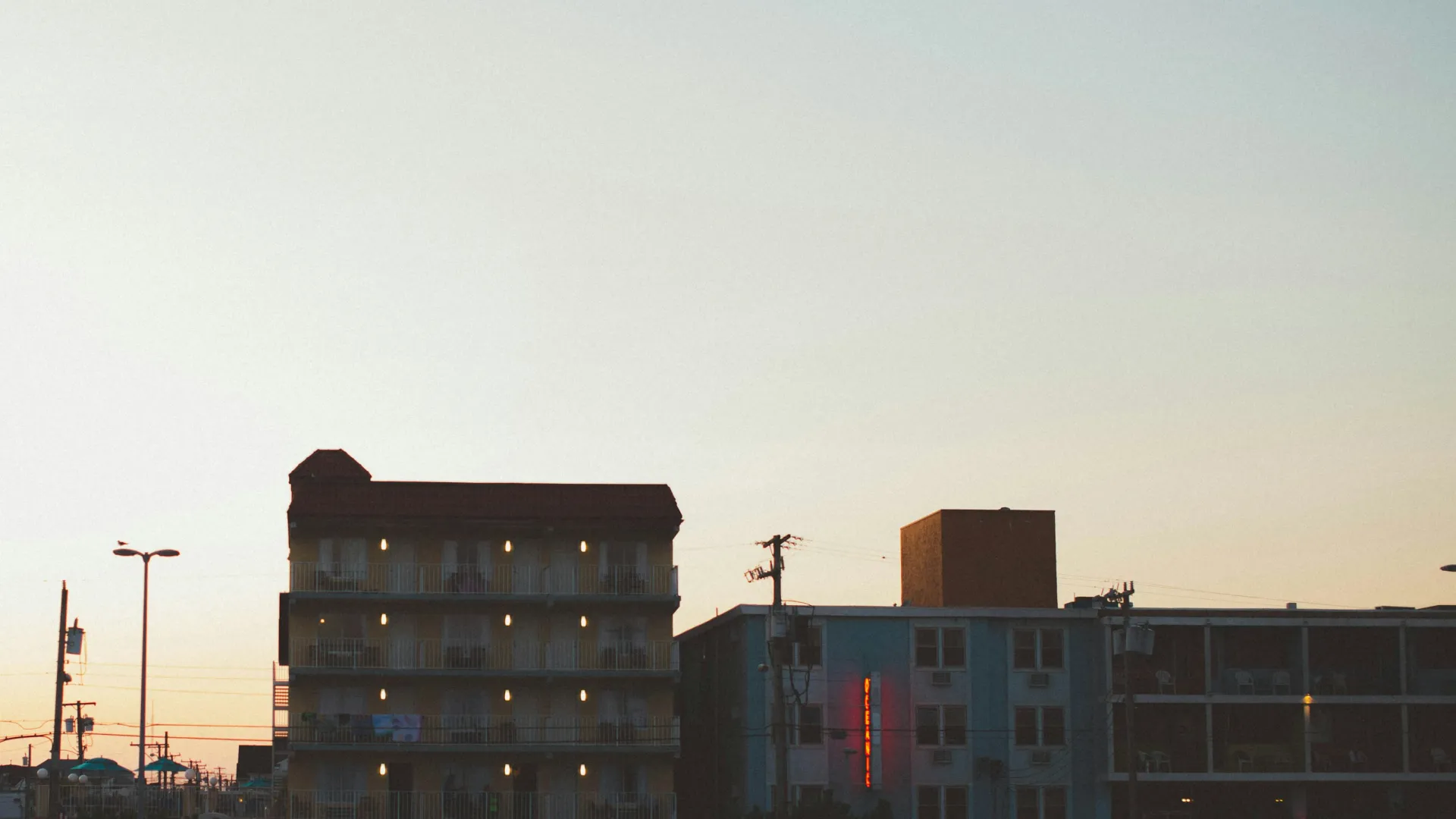 Evening view of lit apartment buildings and power lines under a clear sky at dusk