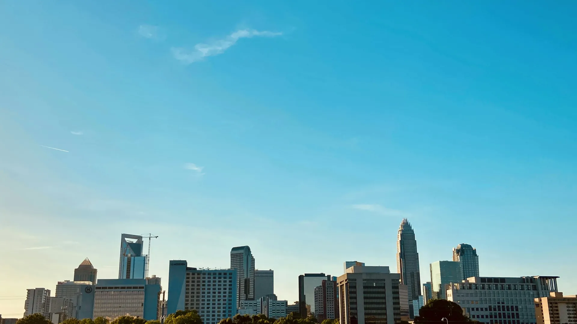 Skyline of a modern city with tall buildings under a clear blue sky at sunset.