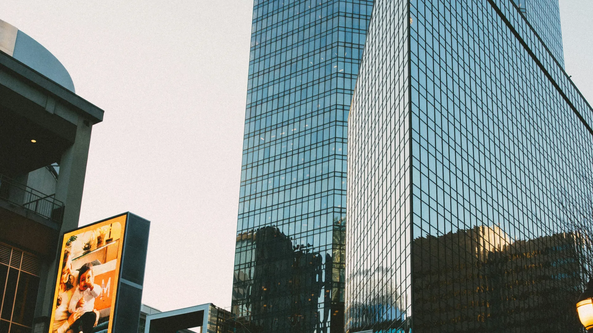 Modern glass skyscrapers with Walgreens store and digital billboard at sunset in urban cityscape.