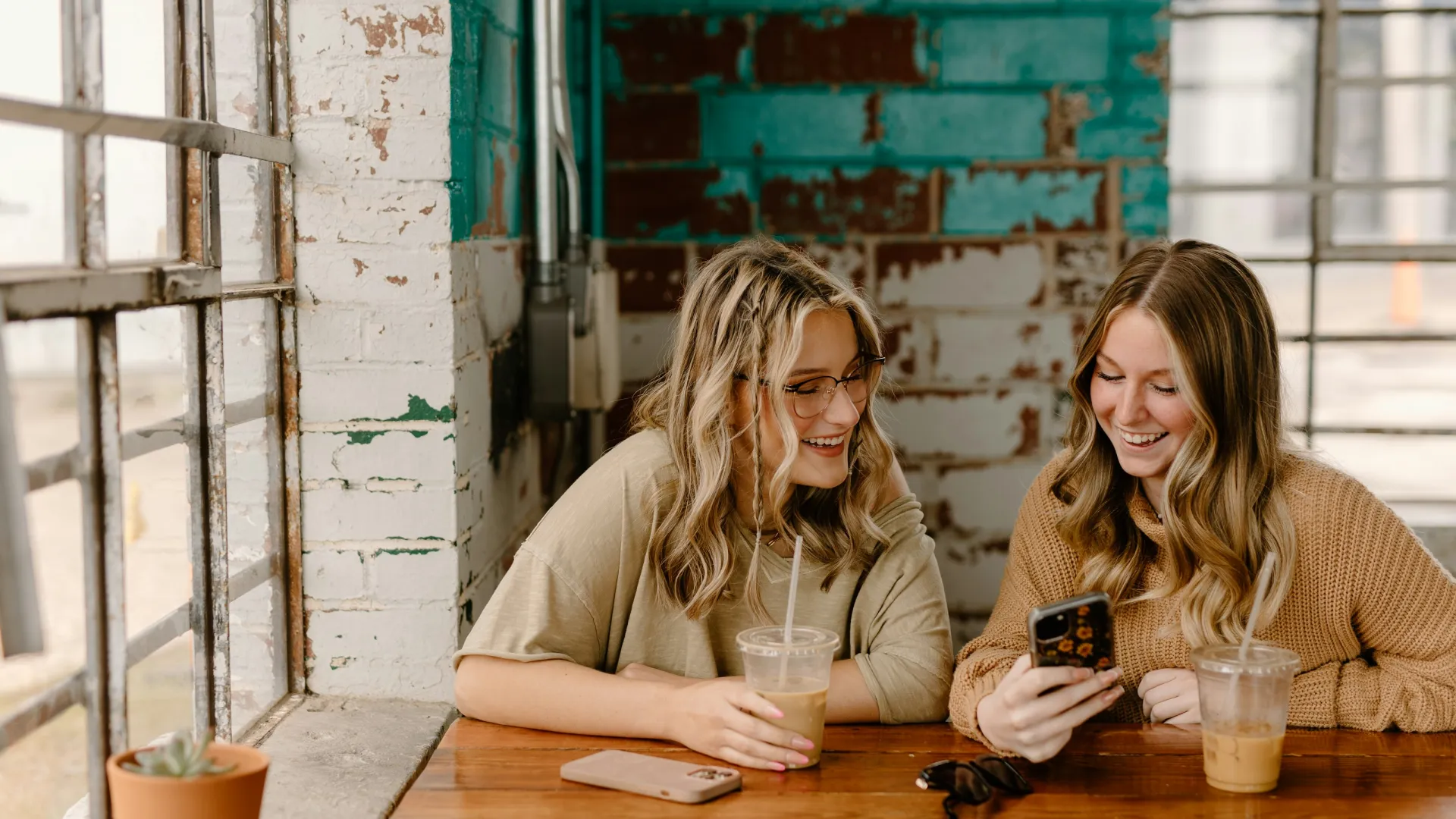 a couple of women sitting at a table looking at a cell phone