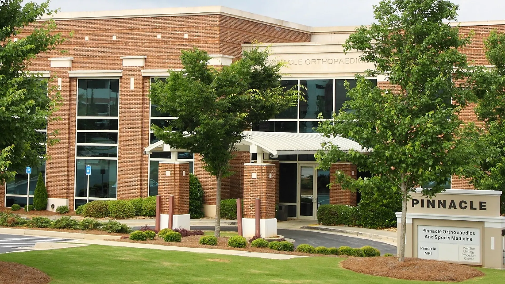 Brick medical office building with trees, lawn, and Pinnacle Orthopaedics and Sports Medicine sign in front