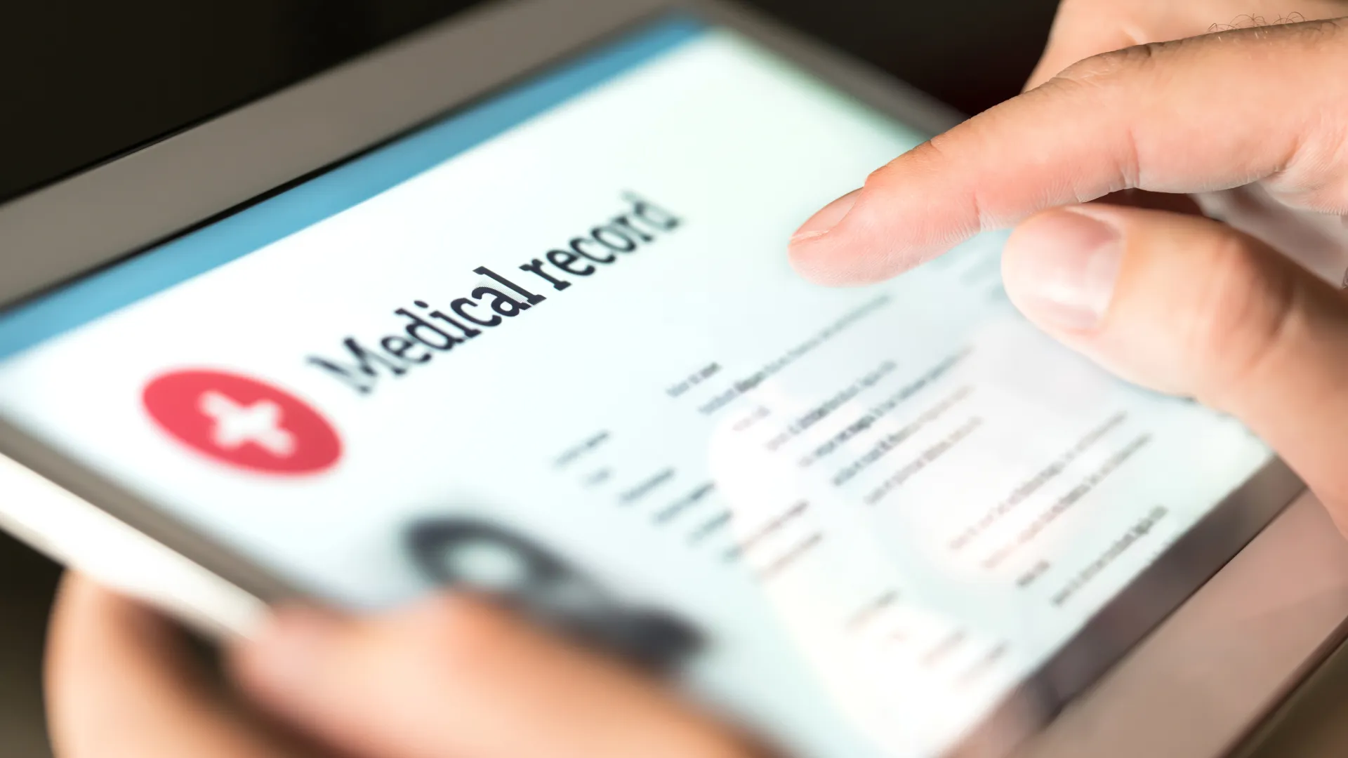 Person reviewing a digital medical record on a tablet with visible health information and icons.