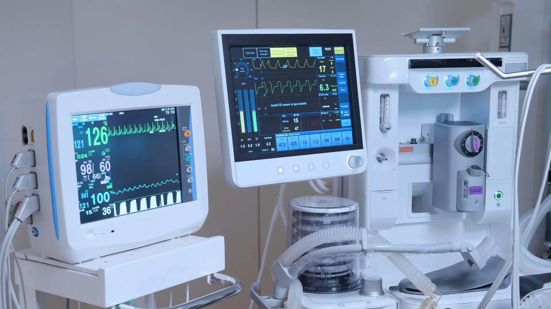 Medical monitors displaying vital signs and anesthesia machine in a hospital operating room setup.