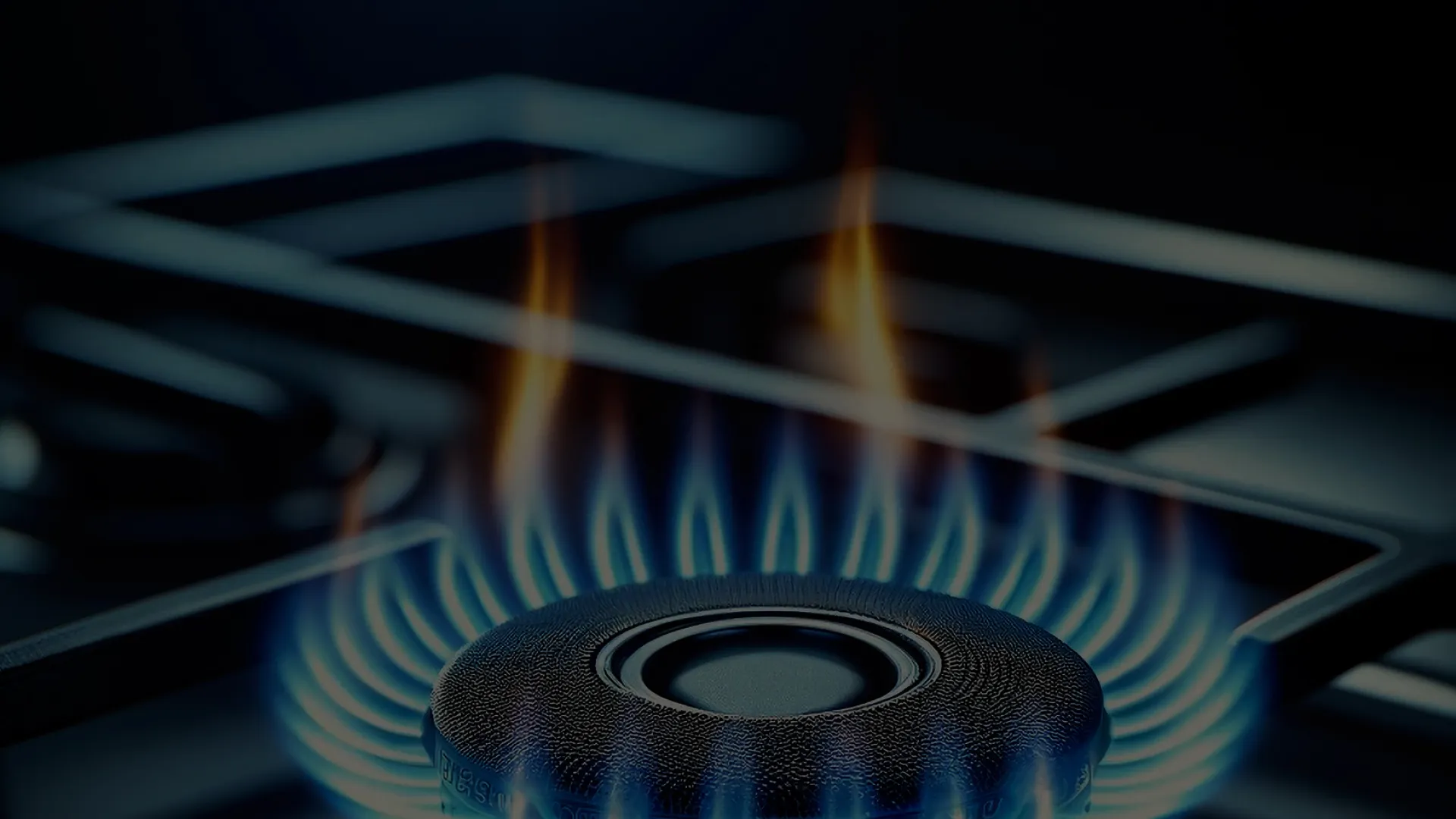 Close-up of a blue gas flame burning evenly on a stove burner in a dark kitchen setting.