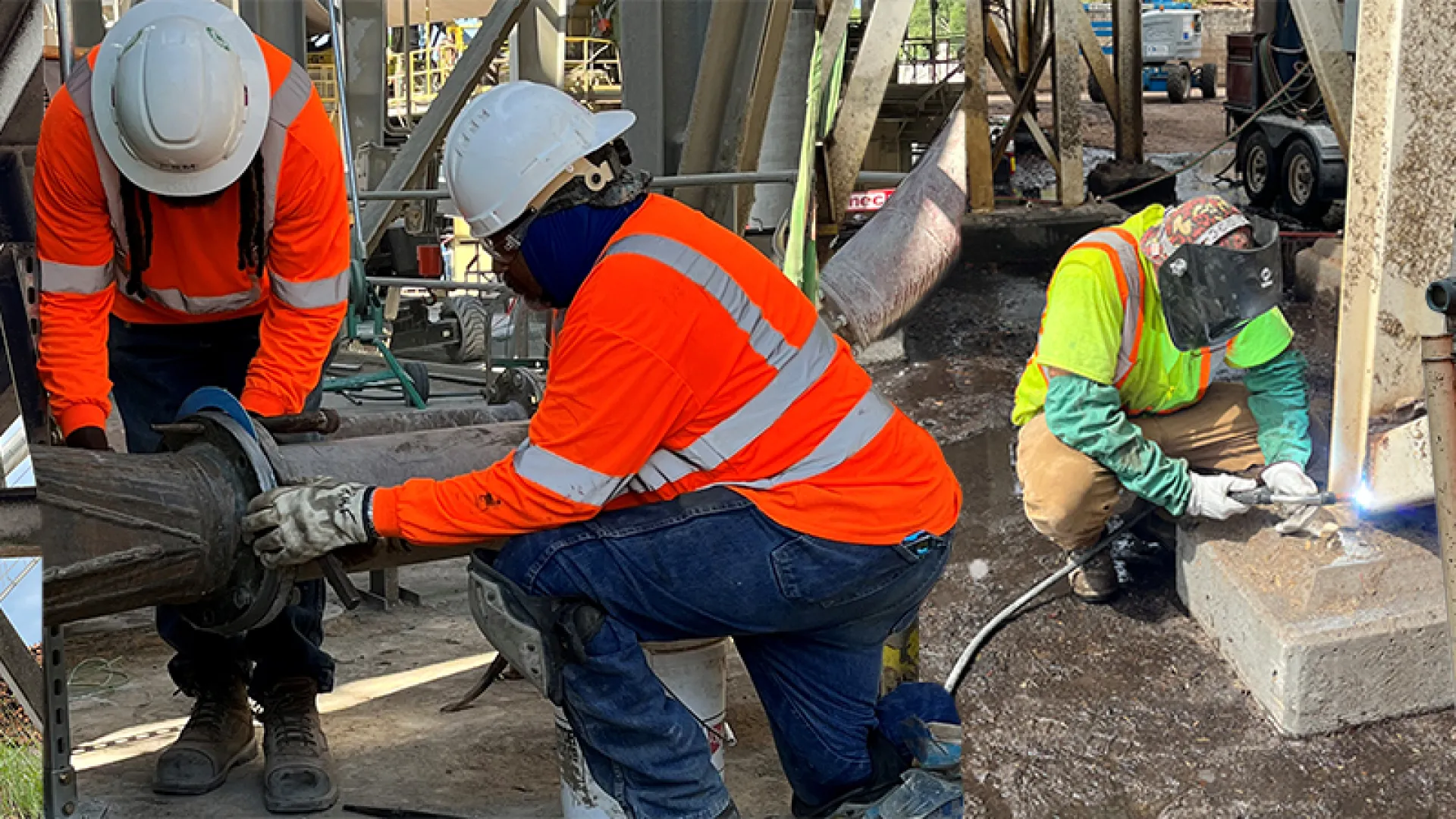 a group of men in orange vests working on a construction site